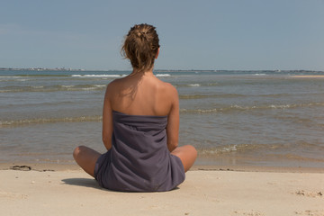 Fototapeta na wymiar Portrait of beautiful woman sitting in yoga pose at beach