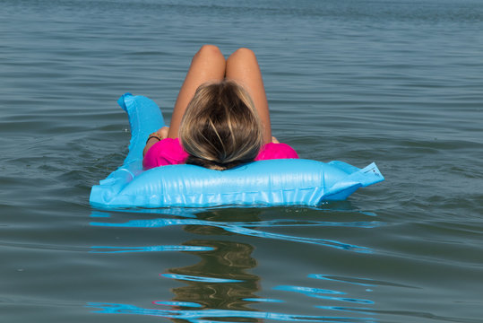 Beach vacation girl relaxing in blue plastic pool air bed