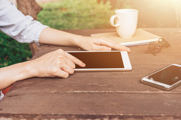 Hand woman using tablet on table in garden at coffee shop with v
