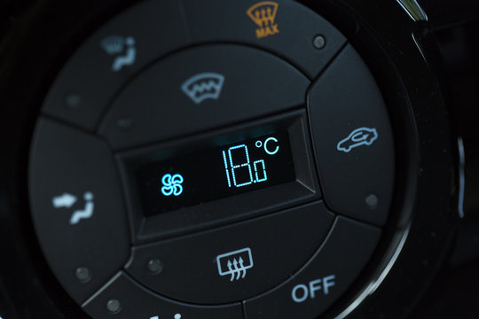 Automatic air condition display says the temperature has been set to 18 celsius degrees. Image taken on a modern brand new car.
