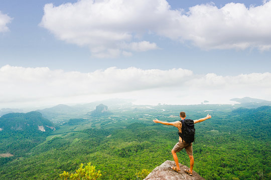 Hiker standing with raised hands and enjoying a beautiful nature from top of mountain.