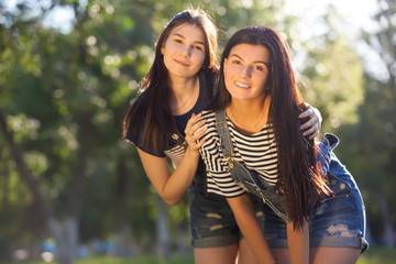 two beautiful young adult sisters hugging and smiling looking at the camera