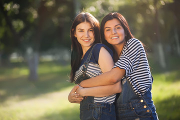 two beautiful young adult sisters hugging and smiling looking at the camera