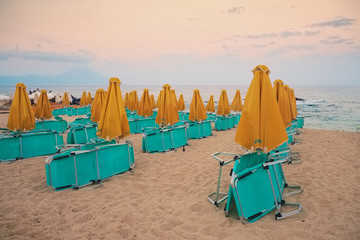 Collapsed deck chairs and umbrellas on the beach