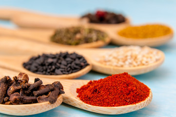 Various spices on wooden spoons. Food ingredients. Blue rustic wood table