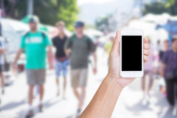 Hand holding mobile phone with blur street market