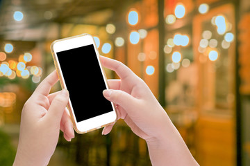 Hand holding mobile phone with blur night light of downtown back