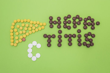 Figure or shape of human liver and the diagnosis of hepatitis A sign made of yellow, brown and white pills or tablets  on a green paper background