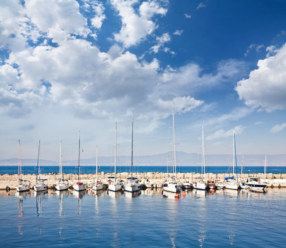 Fototapeta Sailing and Fishing Boats in a Harbour under a Cloudy Sky