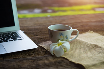 Laptop with a cup of coffee on the old wooden table, working, bright, happy.