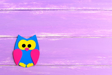 Cute paper owl isolated on a bright wooden background with blank space for text. Children paper crafts. Children art in kindergarten and at home. Kids background