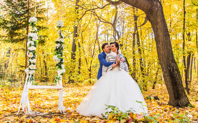 The bride and groom on a swing in autumn park