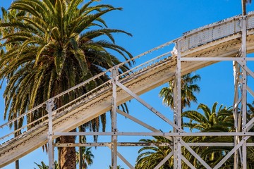 Old rollercoaster against sky and palm tree