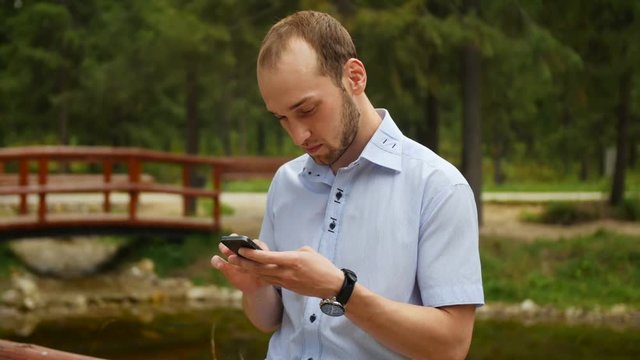 Man using mobile smart phone in park, iphon style.