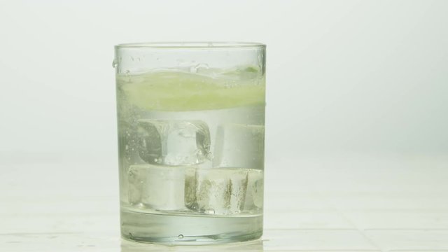 Closeup of lime dropping into carbonated drink