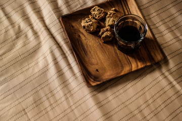 Chocolate chip cookies with the coffee on a wooden plate at the bedroom.
