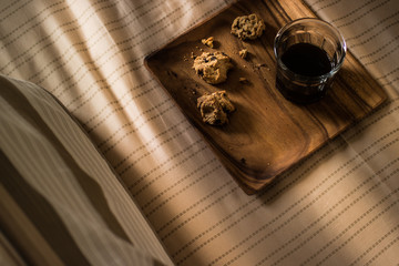 Chocolate chip cookies with the coffee on a wooden plate at the bedroom.
