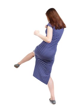 skinny woman funny fights waving his arms and legs. Isolated over white background. The brunette in a blue striped dress stands sideways beats foot.
