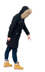 Naklejka premium Back view of pointing young women in parka. girl in warm winter jacket is black with cancer and is pointing down.