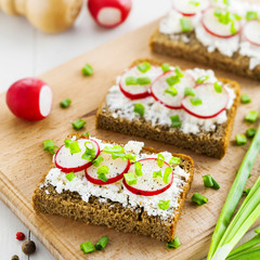 Open sandwiches with soft cream cheese and fresh radish. Summer food on table.