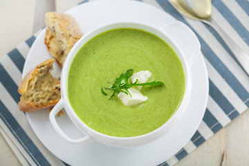 Broccoli cream soup with bread on a table. Classic European food. Top view. Close-up shot..