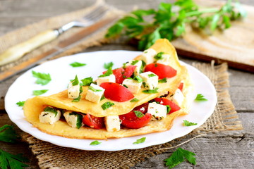 Fototapeta na wymiar Omelette with cheese, tomatoes and parsley on a plate on old wooden background. Stuffed omelette dish. Vintage style. Closeup