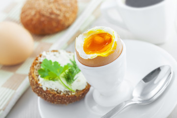 Breakfast with perfect soft boiled egg, sandwich with cheese and coffee on a table. Traditional homemade food.