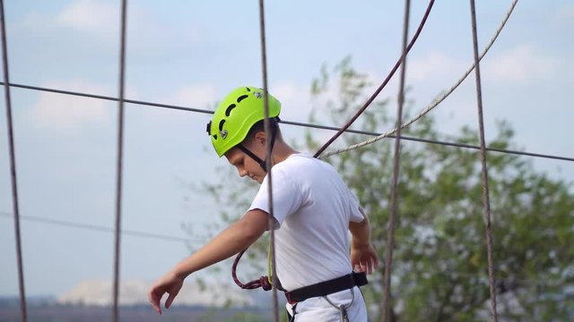 Teenager in hard hat goes on the cable car. He holds on to the ropes