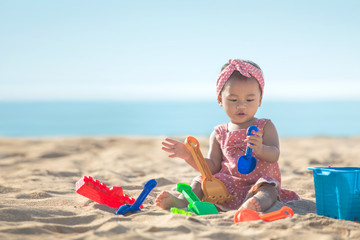 baby girl playing with beach toys at the beach