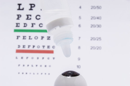 The figure of the eye with eye drops for the treatment or against allergies over it on the background of the table for visual acuity testing (traditional Snellen chart)