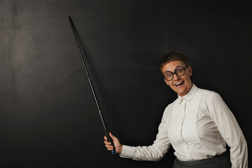 Funny woman teacher with smiling stupid face in round glasses happily shows something with her...