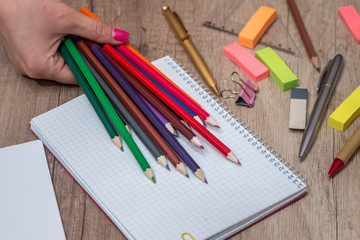 Girl drawing on empty note with colorful pencils on  wooden table