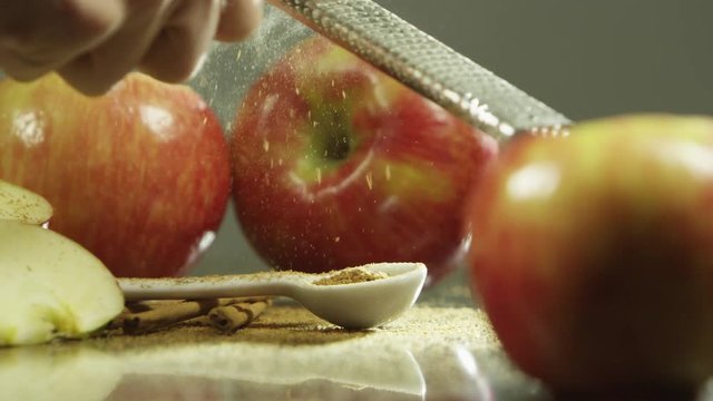 Zesting cinnamon sticks over apples