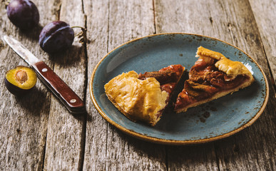 Homemade Rustic Plum Tart with cinnamon, galette on a rough wooden background. Selective focus. Toned 