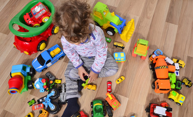 Toddler sitting on the floor surrounded by car toys