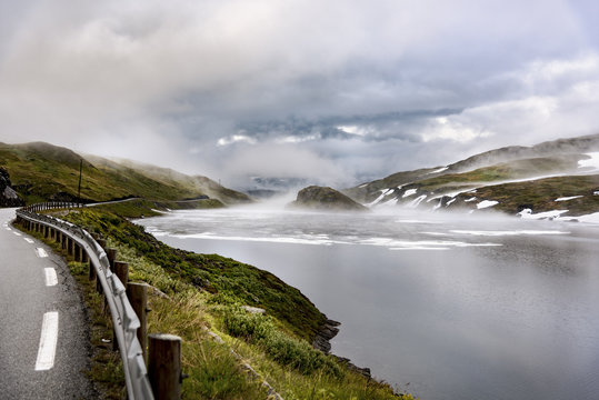 Norway, Hedmark, Tufsindalen valley, road, Gomma river and clouds in spring