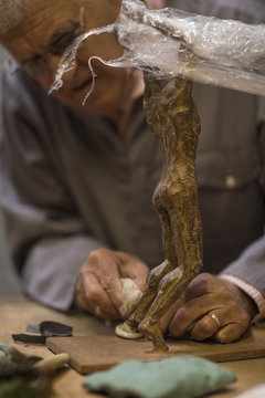 Senior man working on bronze figurine