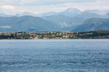 Fototapeta premium Landscape of the coast of Sirmione peninsula which divides the lower part of Lake Garda. It is a famous vacation place for a long time in northern Italy.