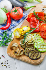 Vegetables roasted on a grill: tomato, corn, eggplant, mushroom, bell pepper, marrow and onion. Delicious healthy food and ingredients on a table. Close-up shot.