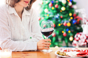 Young woman, drinking wine and having snack at home on christmas