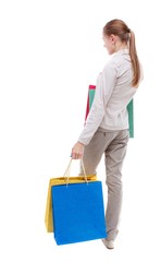 back view of woman with shopping bags. Isolated over white background. Skinny girl in white denim suit standing with paper bags.