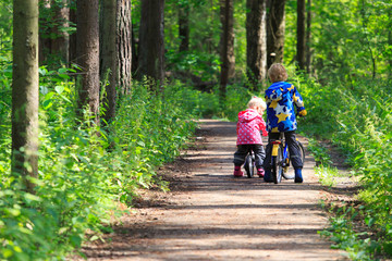 Fototapeta premium kids sport - little boy and girl riding bikes in forest