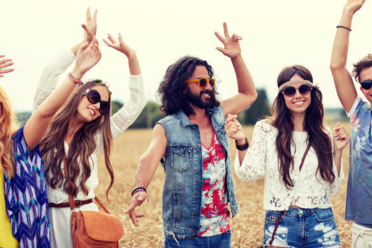 happy young hippie friends dancing on cereal field
