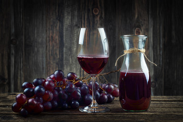 Rotwein im Glas mit frischen roten Trauben - rustikal
