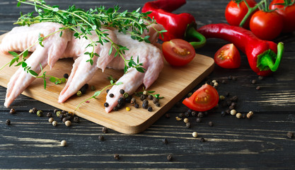 Raw chicken wings with thyme, chili, pepper and tomatoes