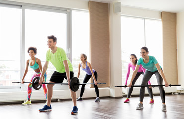 happy people exercising with barbell bars in gym