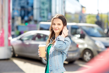 happy young woman drinking coffee on city street