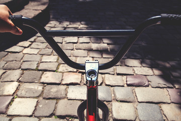 Fototapeta na wymiar Close up of a black handlebar of BMX bicycle in summer day on a pavement backgroung