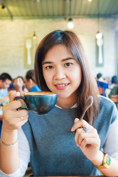Asian woman drinking hot latte coffee at cafe