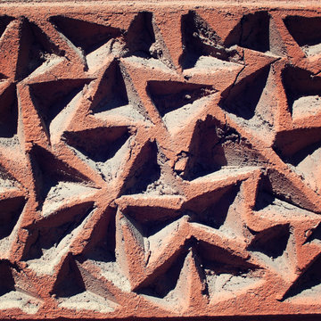 Triangular grooves in the concrete wall. Building decoration close up. Aged photo. Shadow-light contrast. Dusty wall texture. Abstract background.
